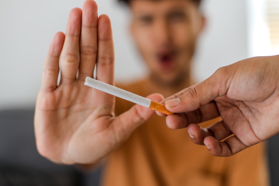 Individu souriant qui rejette la cigarette, symbole de liberté retrouvée